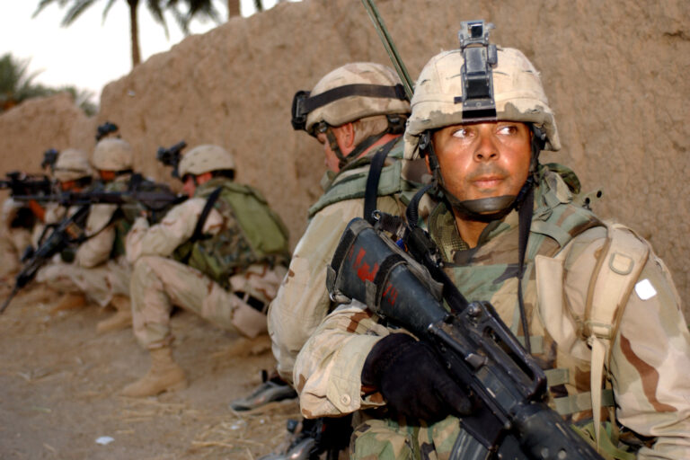 A group of soldiers taking cover behind a wall while on a mission in Iraq