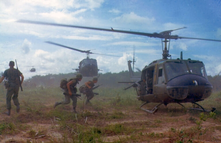 Soldiers in the Vietnam War rush to load onto Huey Helicopters in a landing zone